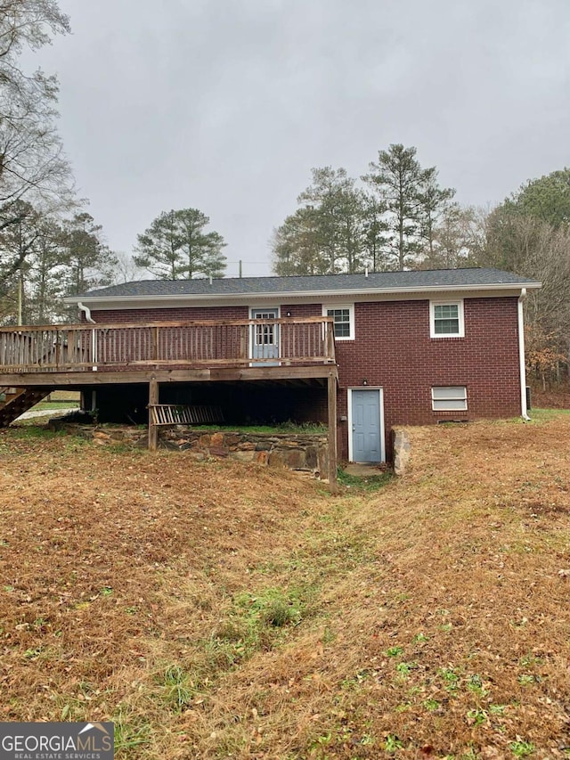 back of property featuring a wooden deck and a yard