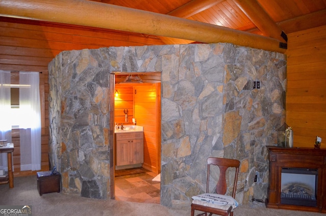 unfurnished living room with beam ceiling, a stone fireplace, wood ceiling, and sink