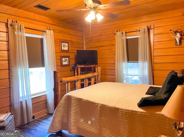 bedroom featuring wood walls, dark hardwood / wood-style floors, ceiling fan, and multiple windows