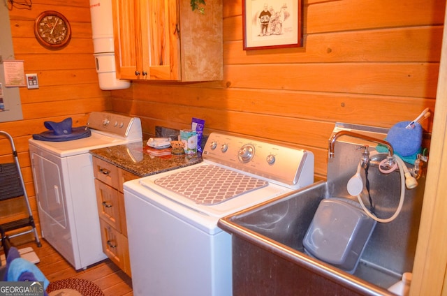 laundry area featuring washer and dryer, cabinets, wooden walls, and light hardwood / wood-style flooring