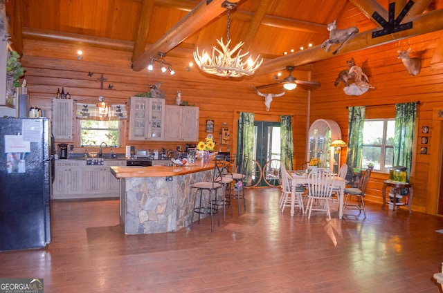 kitchen with beam ceiling, black refrigerator, wood ceiling, and wood-type flooring