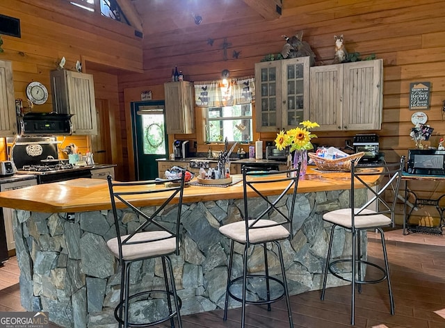 kitchen with wood walls, lofted ceiling, hardwood / wood-style flooring, a kitchen island, and range