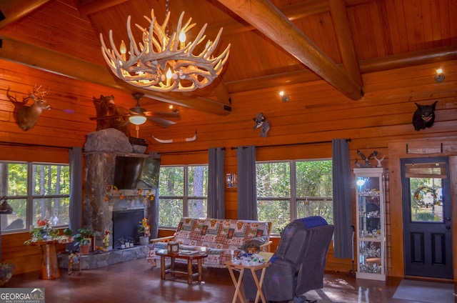 living room featuring beam ceiling, a stone fireplace, wooden ceiling, and a wealth of natural light