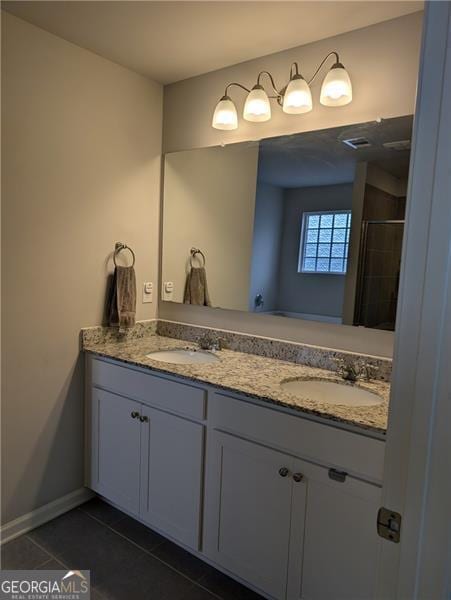 bathroom featuring tile patterned flooring, vanity, and a shower