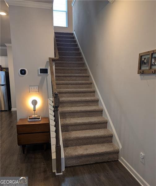 staircase with hardwood / wood-style floors and crown molding