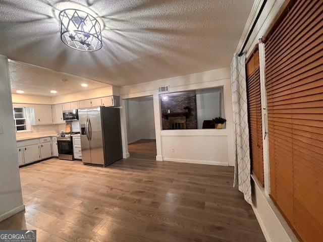 kitchen with white cabinetry, stainless steel appliances, a barn door, dark hardwood / wood-style flooring, and a textured ceiling