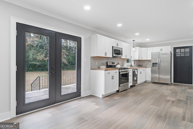 kitchen featuring white cabinetry, hanging light fixtures, and appliances with stainless steel finishes