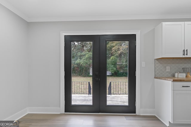 doorway with french doors, light wood-type flooring, and ornamental molding