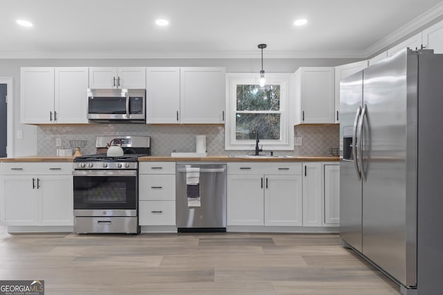 kitchen featuring white cabinetry, sink, decorative light fixtures, and appliances with stainless steel finishes