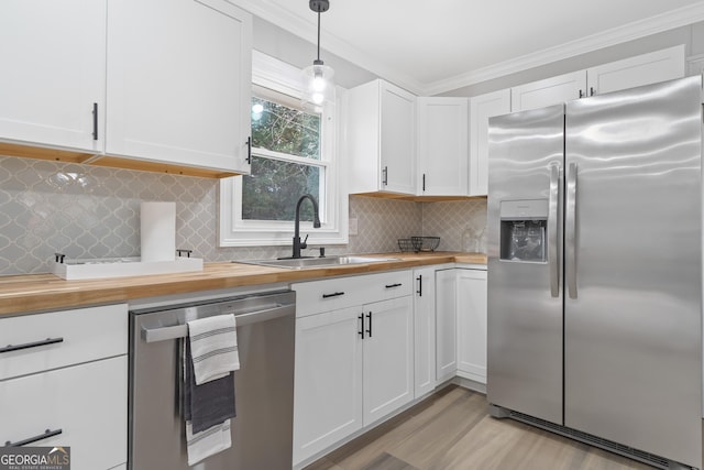 kitchen with white cabinetry, sink, decorative light fixtures, and appliances with stainless steel finishes