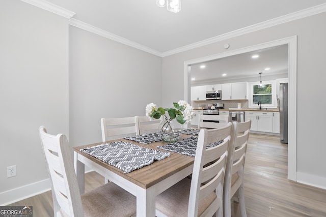 dining area featuring light hardwood / wood-style flooring, crown molding, and sink