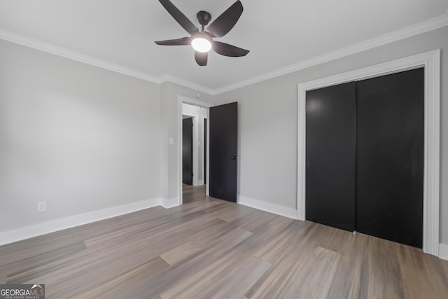 unfurnished bedroom with light wood-type flooring, a closet, crown molding, and ceiling fan