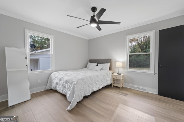 bedroom featuring multiple windows, ceiling fan, hardwood / wood-style floors, and ornamental molding