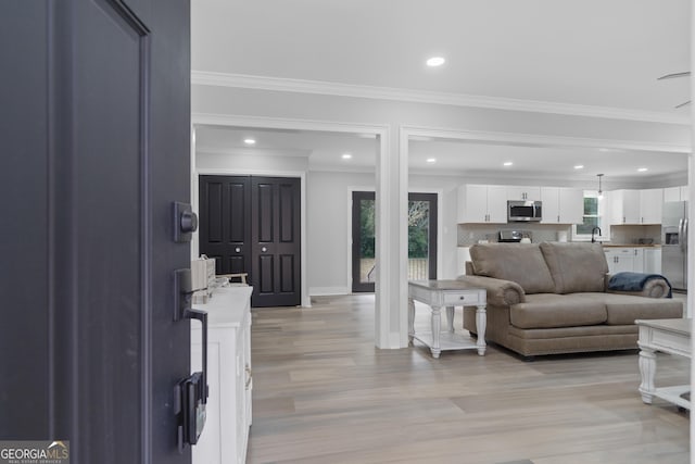 living room featuring light hardwood / wood-style floors, plenty of natural light, ornamental molding, and sink