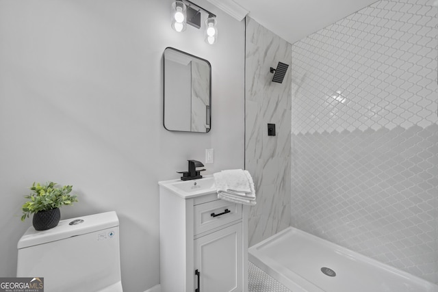 bathroom featuring a tile shower, vanity, and toilet