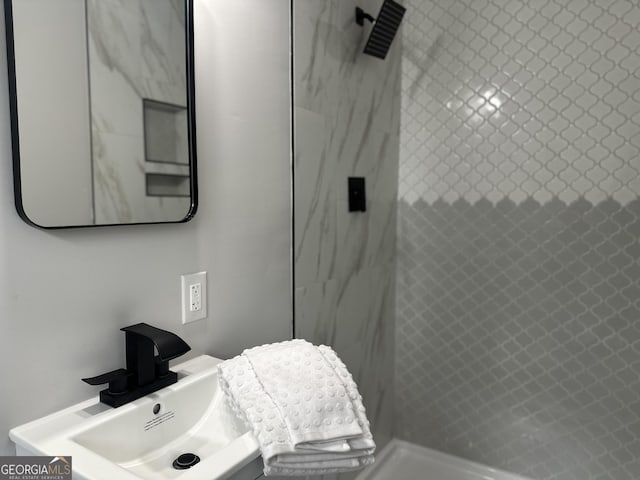 bathroom with a tile shower and sink