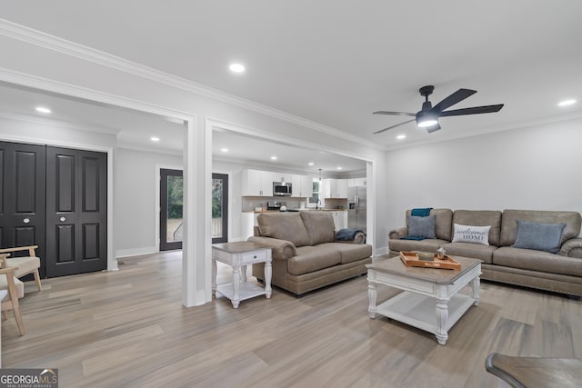 living room with light wood-type flooring, ceiling fan, and crown molding