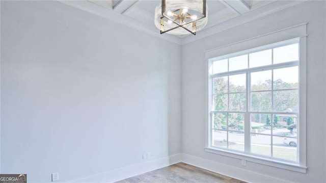 empty room with a chandelier, beam ceiling, hardwood / wood-style flooring, and coffered ceiling