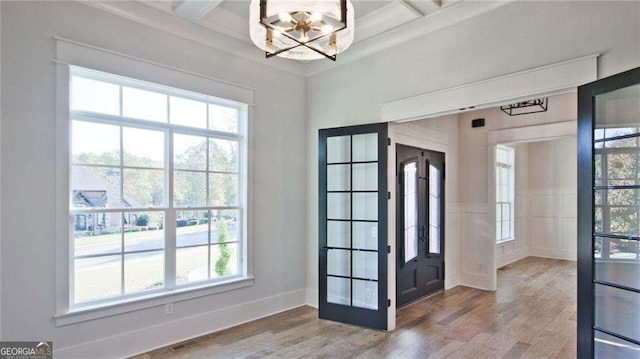 foyer featuring beamed ceiling, a healthy amount of sunlight, and hardwood / wood-style flooring