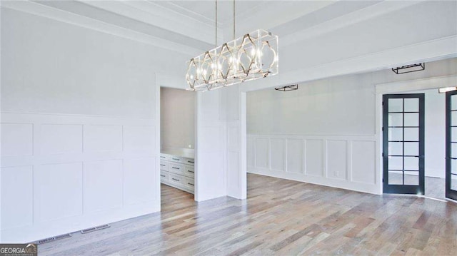 unfurnished dining area featuring a notable chandelier, light wood-type flooring, and french doors