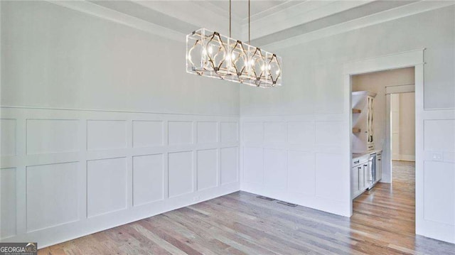 unfurnished dining area with a chandelier and light hardwood / wood-style flooring