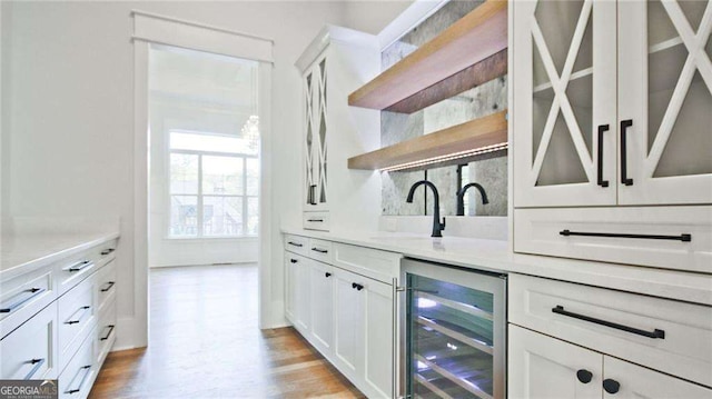 bar featuring white cabinets, sink, wine cooler, and light hardwood / wood-style flooring