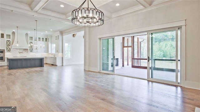 unfurnished living room with light hardwood / wood-style flooring, a healthy amount of sunlight, and coffered ceiling