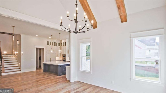 kitchen featuring vaulted ceiling with beams, a center island, light hardwood / wood-style floors, and an inviting chandelier