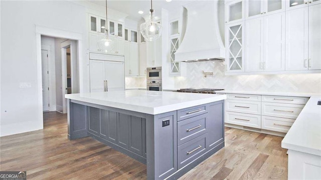 kitchen with white cabinets, a center island, premium range hood, and stainless steel appliances