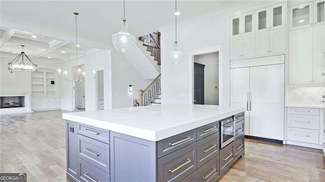 kitchen with white cabinetry, hanging light fixtures, coffered ceiling, hardwood / wood-style floors, and paneled built in fridge