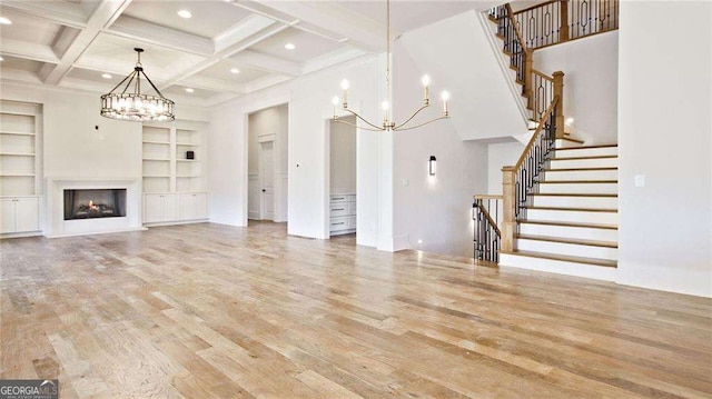 unfurnished living room featuring beam ceiling, light hardwood / wood-style flooring, built in shelves, and coffered ceiling