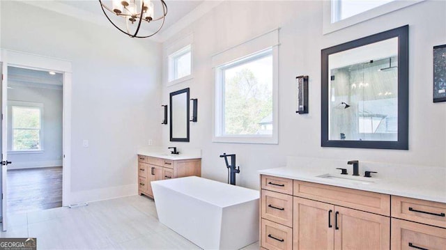 bathroom with plenty of natural light, a tub to relax in, vanity, and a chandelier