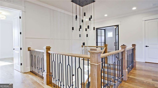 hallway with light hardwood / wood-style floors and ornamental molding