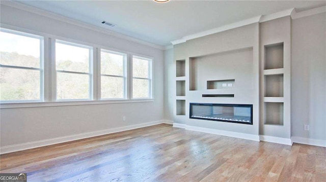 unfurnished living room with built in features, light wood-type flooring, and crown molding