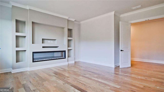 unfurnished living room featuring built in shelves, crown molding, and light wood-type flooring