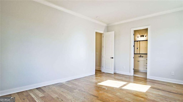 unfurnished bedroom featuring ensuite bathroom, hardwood / wood-style floors, and ornamental molding