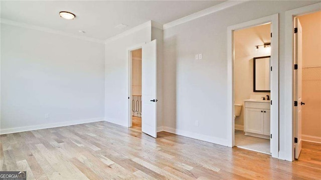 unfurnished bedroom featuring ensuite bathroom, ornamental molding, and light hardwood / wood-style flooring