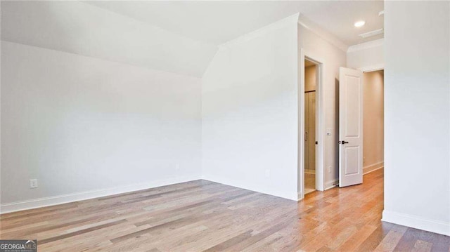 unfurnished room featuring lofted ceiling and light wood-type flooring