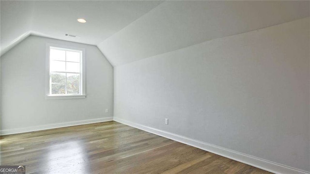 additional living space featuring wood-type flooring and lofted ceiling