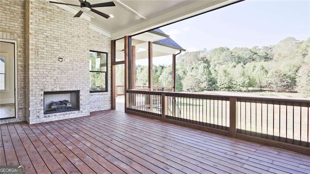 wooden terrace featuring ceiling fan and an outdoor brick fireplace