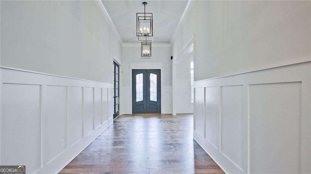 entrance foyer featuring hardwood / wood-style flooring, a chandelier, ornamental molding, and french doors