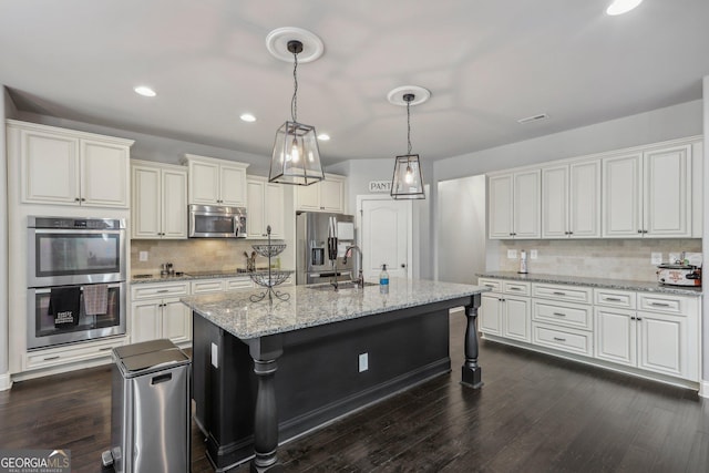 kitchen featuring sink, tasteful backsplash, dark hardwood / wood-style flooring, an island with sink, and appliances with stainless steel finishes