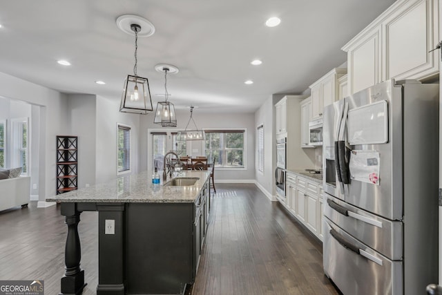 kitchen with sink, hanging light fixtures, dark hardwood / wood-style floors, a kitchen island with sink, and appliances with stainless steel finishes