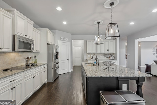 kitchen featuring dark hardwood / wood-style flooring, stainless steel appliances, a kitchen island with sink, sink, and white cabinetry