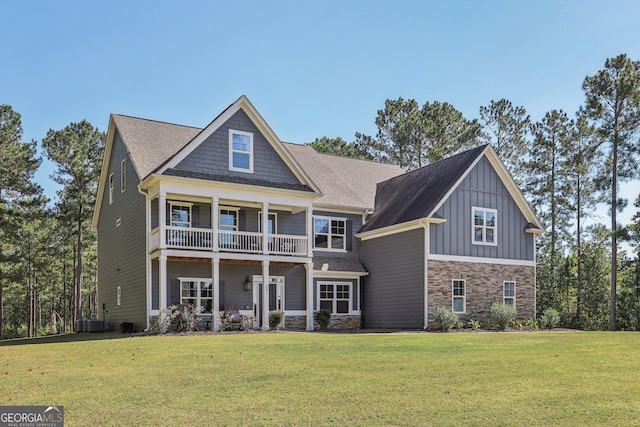 view of front of house featuring a balcony, central AC, and a front lawn