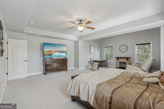 bedroom featuring ceiling fan, a stone fireplace, and light carpet