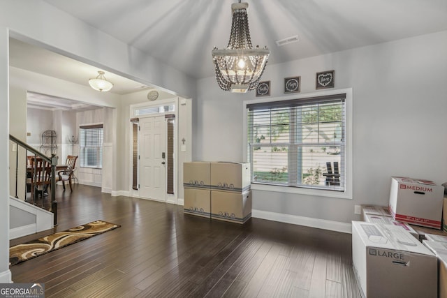 entrance foyer with dark hardwood / wood-style floors and an inviting chandelier