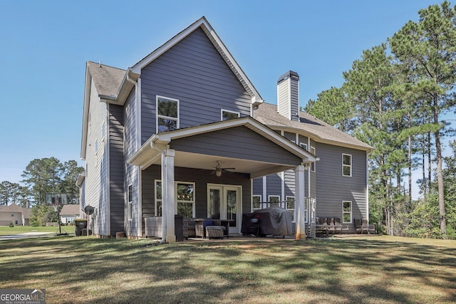 rear view of property featuring ceiling fan and a yard