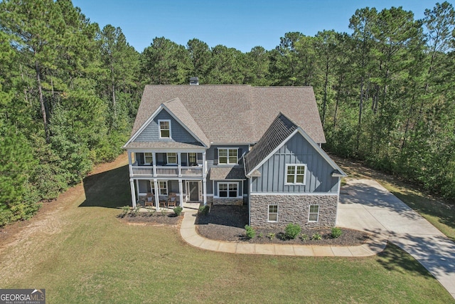 back of house featuring covered porch, a balcony, and a lawn