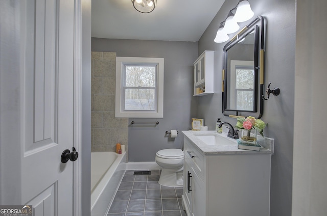 bathroom featuring tile patterned floors, a tub to relax in, vanity, and toilet